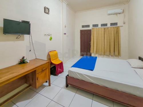 a bedroom with a bed and a desk and a television at Griya Tambun Raya RedPartner in Tumbangrungan