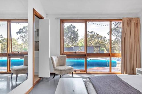 a bedroom with a view of a pool through windows at Nature's Edge - A Parkland Escape for Families in Adelaide
