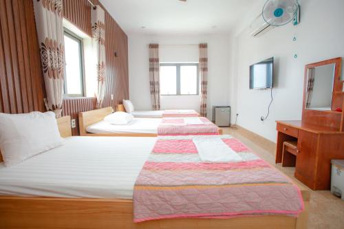 Cette chambre comprend 3 lits et une télévision. dans l'établissement KHÁNH GIA HOTEL, à Tam Kỳ