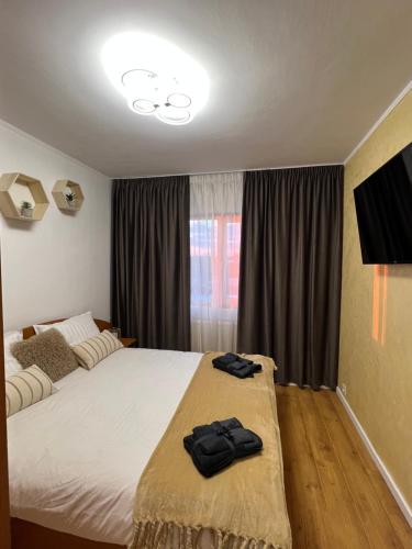 a bedroom with a bed with two black towels on it at Best Rent Apartments in Giurgiu