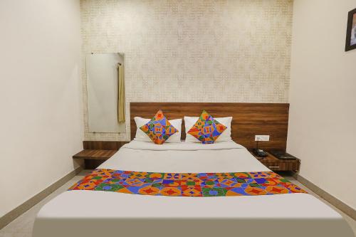 a bedroom with a large white bed with colorful pillows at FabHotel Prince Mama in Gwalior