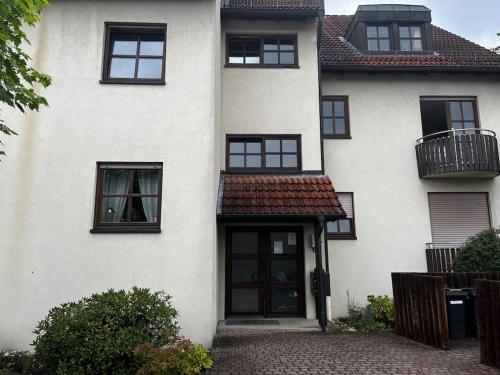 uma casa branca com janelas pretas e uma porta em Cozy&spacious topfloor apartment em Schwaig bei Nürnberg