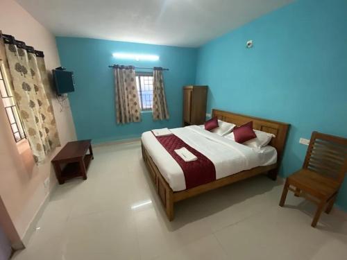 een slaapkamer met een bed en een stoel en blauwe muren bij J J HOMES in Ooty
