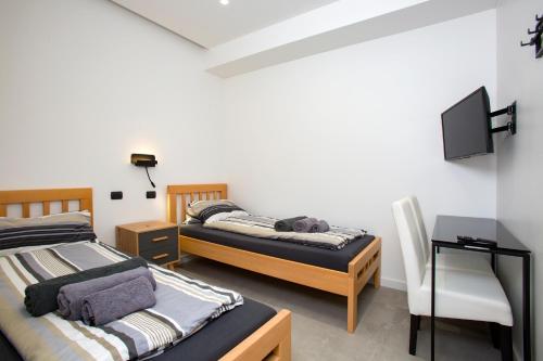 two beds in a room with a tv and a chair at Villa Rita Pool & Spa in Mascalucia