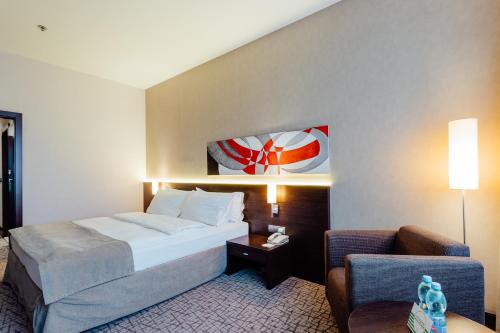 a hotel room with a bed and a chair at Holiday Inn Zilina by IHG in Žilina