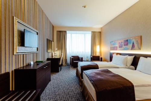 a hotel room with two beds and a flat screen tv at Holiday Inn Zilina by IHG in Žilina