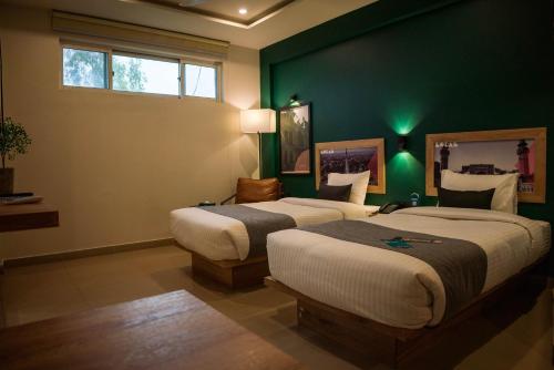 duas camas num quarto com paredes verdes em LOKAL Rooms x Lahore (Cavalry) em Lahore