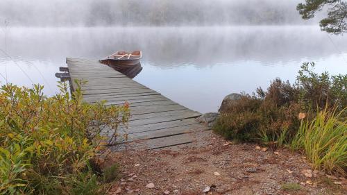 a boat sitting at the end of a dock on a lake at Långasjönäs Camping & Stugby in Karlshamn