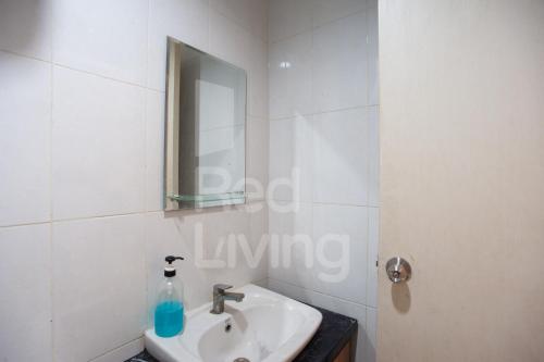 a white bathroom with a sink and a mirror at RedLiving Apartemen Patra Land Urbano - Iconic Room Tower Mid-West in Bulanbulan