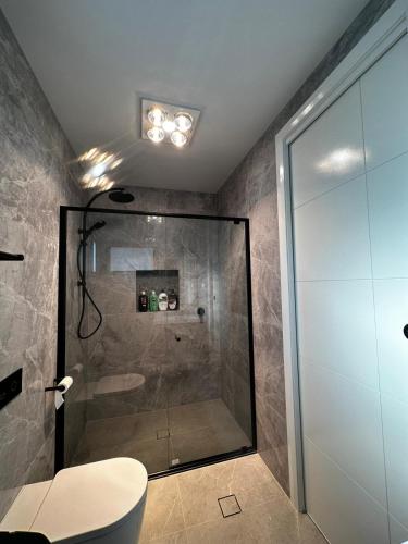 a bathroom with a shower with a toilet and a glass shower stall at Executive Suite in Strathnairn