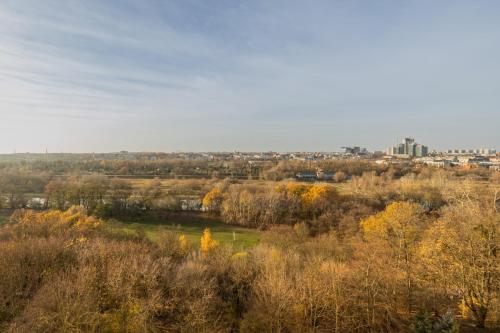 a field with trees and a city in the background at Apartment Near the Warta River by Renters in Poznań