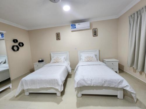una camera con due letti con lenzuola bianche e una finestra di استراحه الليوان ALliwan Rak 1 a Ras al Khaimah