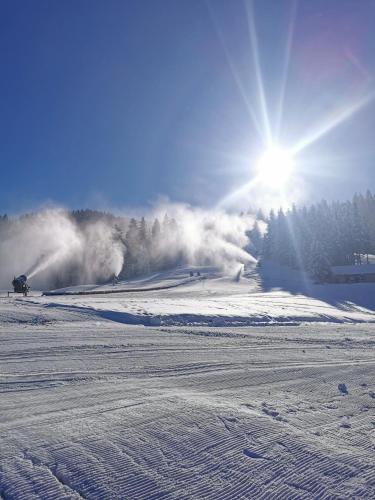 a snow covered slope with the sun in the sky at Apartmajsko naselje Ribniško Pohorje in Ribnica na Pohorju