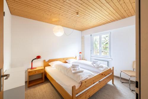 een slaapkamer met een groot bed en een houten plafond bij Brentsch A23 in Scuol