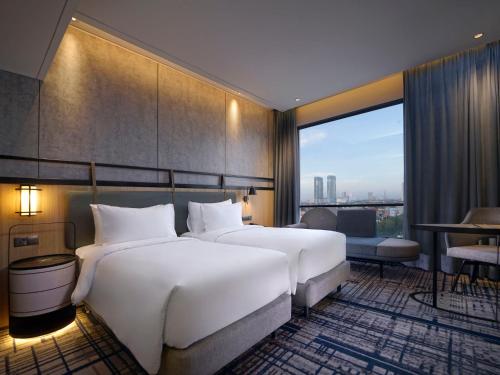 Habitación de hotel con 2 camas y ventana grande. en Mercure Surabaya Manyar en Surabaya