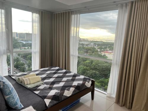 a bedroom with a bed and a large window at De Luxe, Standard and Studio Suites -The Breeze Residences-close to Airport,Mall of Asia, US Embassy in Manila