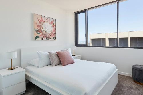 a white bedroom with a bed and a window at City Lights & Manhattan Heights - A Gem in Melbourne in Melbourne