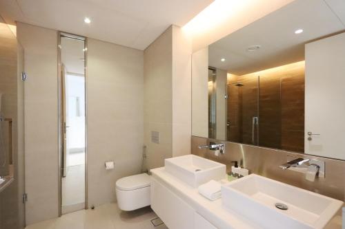a bathroom with a sink and a toilet and a mirror at Luxurious 2 BR in Bluewater w/Sea View by Livbnb in Dubai