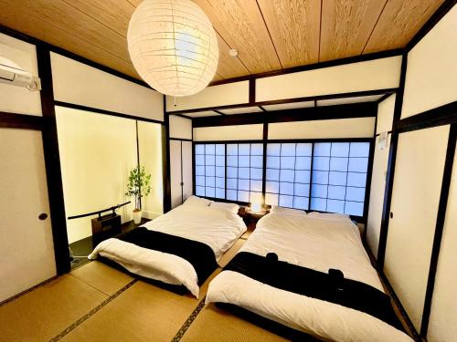 2 Betten in einem Zimmer mit 2 Fenstern in der Unterkunft push house 伊東 in Ito