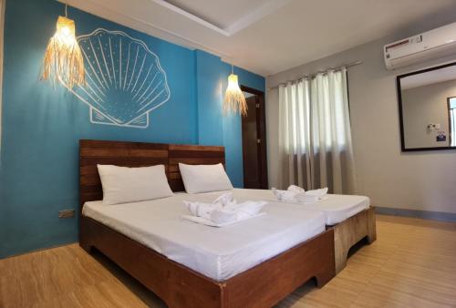 a bedroom with a bed with white sheets and a blue wall at Amos Pili Tree Inn powered by Cocotel in El Nido