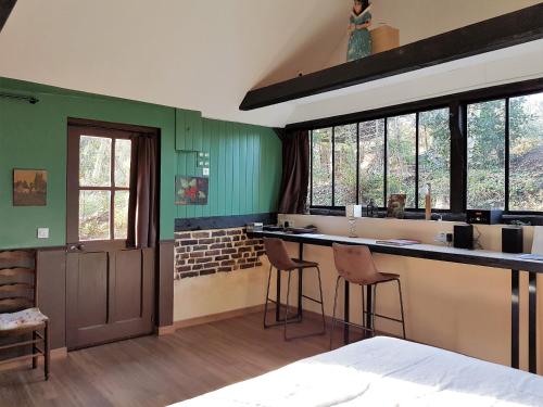 une cuisine avec des murs verts et un comptoir avec des tabourets dans l'établissement Maison Rouge, à Varengeville-sur-Mer