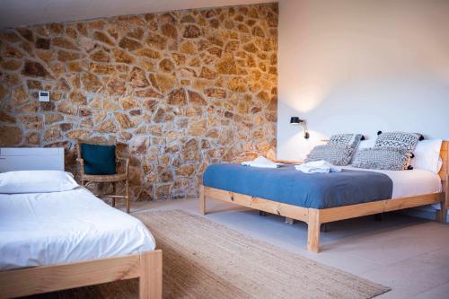 1 dormitorio con 2 camas y pared de piedra en CAN BUFÍ Espectacular casa con piscina interior, en Llagostera