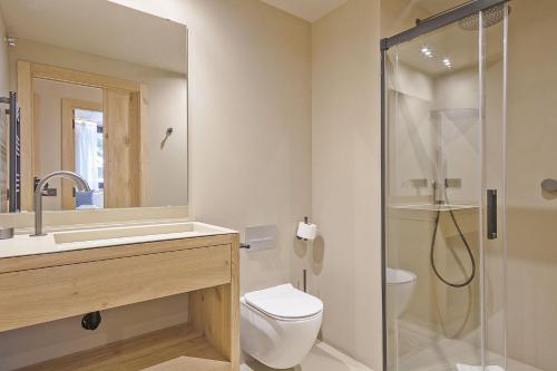 a bathroom with a toilet and a glass shower at Luderna - Apartamento con jardín Marconi in Arties