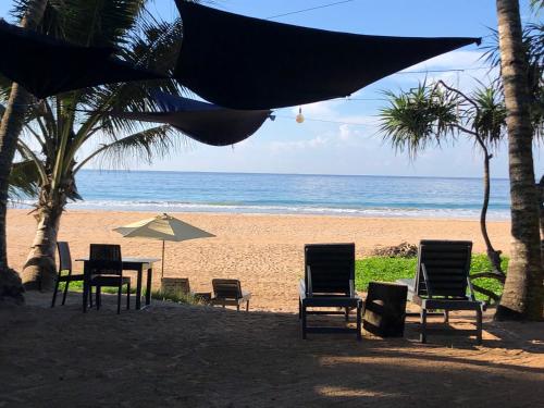 a table and chairs and an umbrella on the beach at Mandy House in Habaraduwa Central