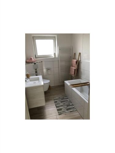 uma casa de banho com uma banheira, um lavatório e um WC. em Ferienwohnung Frank 80qm em Bad Emstal