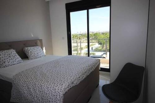 a bedroom with a bed and a chair and a window at COSTA ELISA20 MIL PALMERAS in La Horadada
