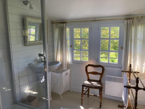 ein Badezimmer mit einem Waschbecken und einem Stuhl darin in der Unterkunft Noyer in Thil-Manneville