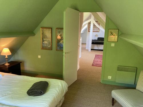 Grünes Zimmer mit einem Bett und einem Stuhl in der Unterkunft Noyer in Thil-Manneville