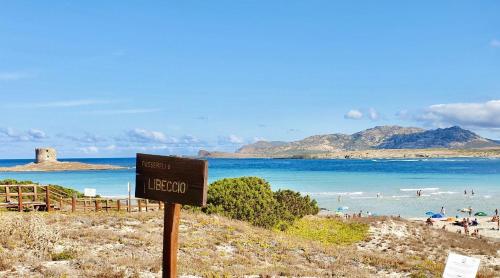 a sign on a beach with people in the water at Villas with air conditioning and shared pool, just a few minutes from La Pelosa beach in Cuile Pazzoni