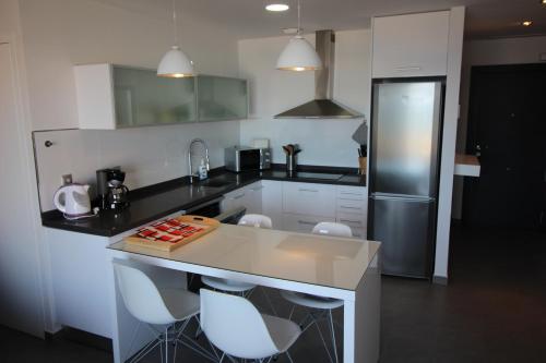 a kitchen with a counter with chairs and a refrigerator at la mata aqua nature in La Mata