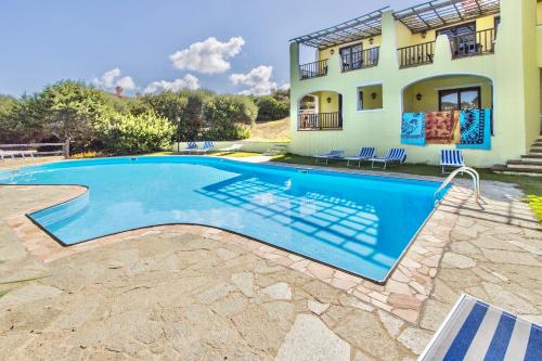 a villa with a swimming pool in front of a house at Villas with air conditioning and shared pool, just a few minutes from La Pelosa beach in Cuile Pazzoni