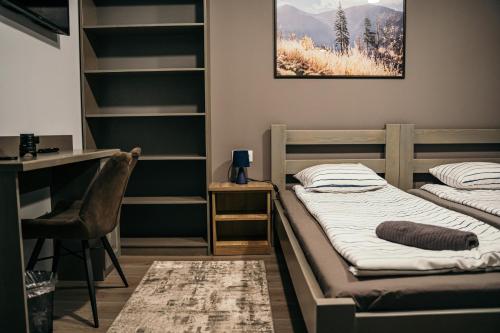 2 Betten in einem Zimmer mit einem Schreibtisch und Regalen in der Unterkunft Ride More Activity Center in Miercurea Ciuc