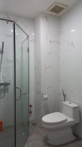 a bathroom with a toilet and a glass shower at Red Bean Hotel in Thuan An