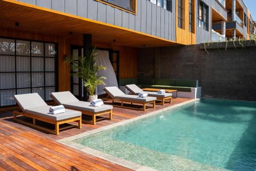 a swimming pool with lounge chairs next to a building at Secana Beachtown in Canggu