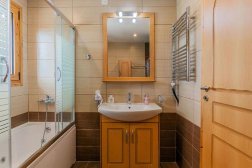 a bathroom with a sink and a mirror and a tub at Villa Giorgos by PosarelliVillas in Gavalochori
