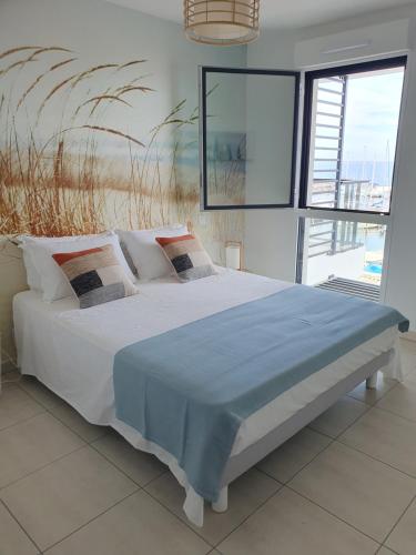 Un dormitorio con una cama con una manta azul. en Appartement standing vue étang de Thau, en Marseillan