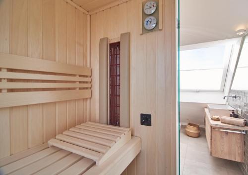 uma sauna com um banco e um relógio na parede em Paradise Suite - Penthouse mit Meerblick em Timmendorfer Strand