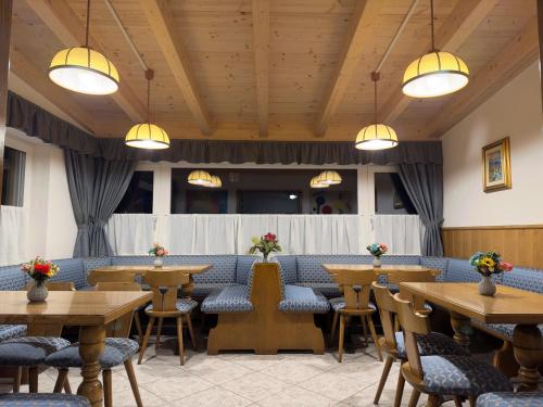 a restaurant with wooden tables and chairs and lights at PANORAMA SportHOTEL in Folgaria