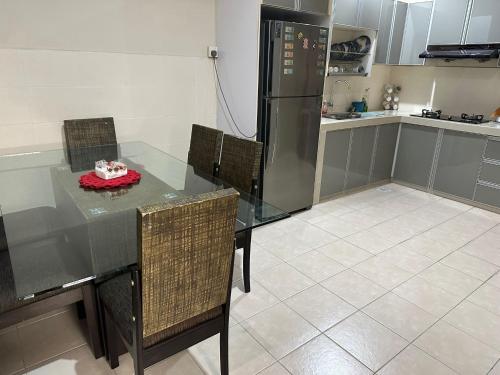 a kitchen with a glass table with chairs and a refrigerator at Semi -D Homestay Seremban 2 in Seremban