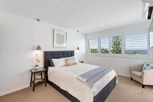 a white bedroom with a bed and a chair at Seashells on Sunrise, Sunrise Beach in Sunrise Beach