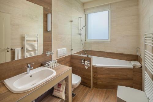 a bathroom with a sink and a toilet and a tub at Mamaison Hotel Andrassy Budapest in Budapest