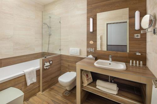a bathroom with a sink and a toilet and a mirror at Mamaison Hotel Andrassy Budapest in Budapest