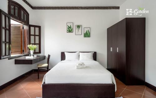 a bedroom with a bed and a desk and a window at 5H Garden in Ho Chi Minh City