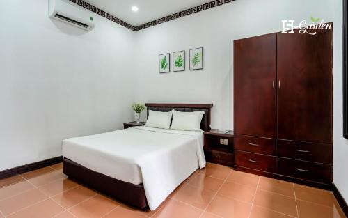 a bedroom with a white bed and a wooden cabinet at 5H Garden in Ho Chi Minh City