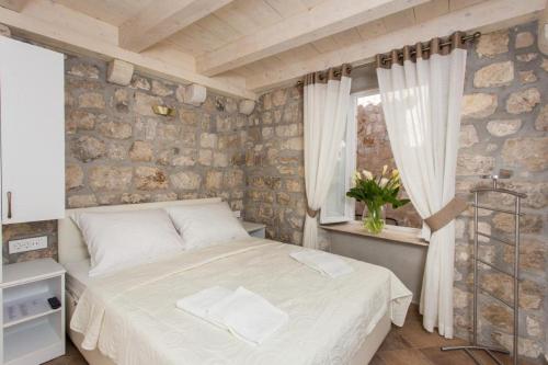 杜布羅夫尼克的住宿－寶緹公寓，一间卧室设有一张床和石墙