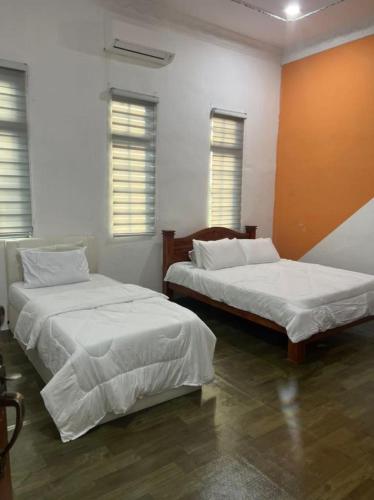 - 2 lits dans une chambre avec 2 fenêtres dans l'établissement Flora inn, à Kota Bharu